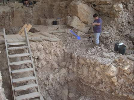 Photograph of the cave during excavation; arrow pointing to the hearth. 